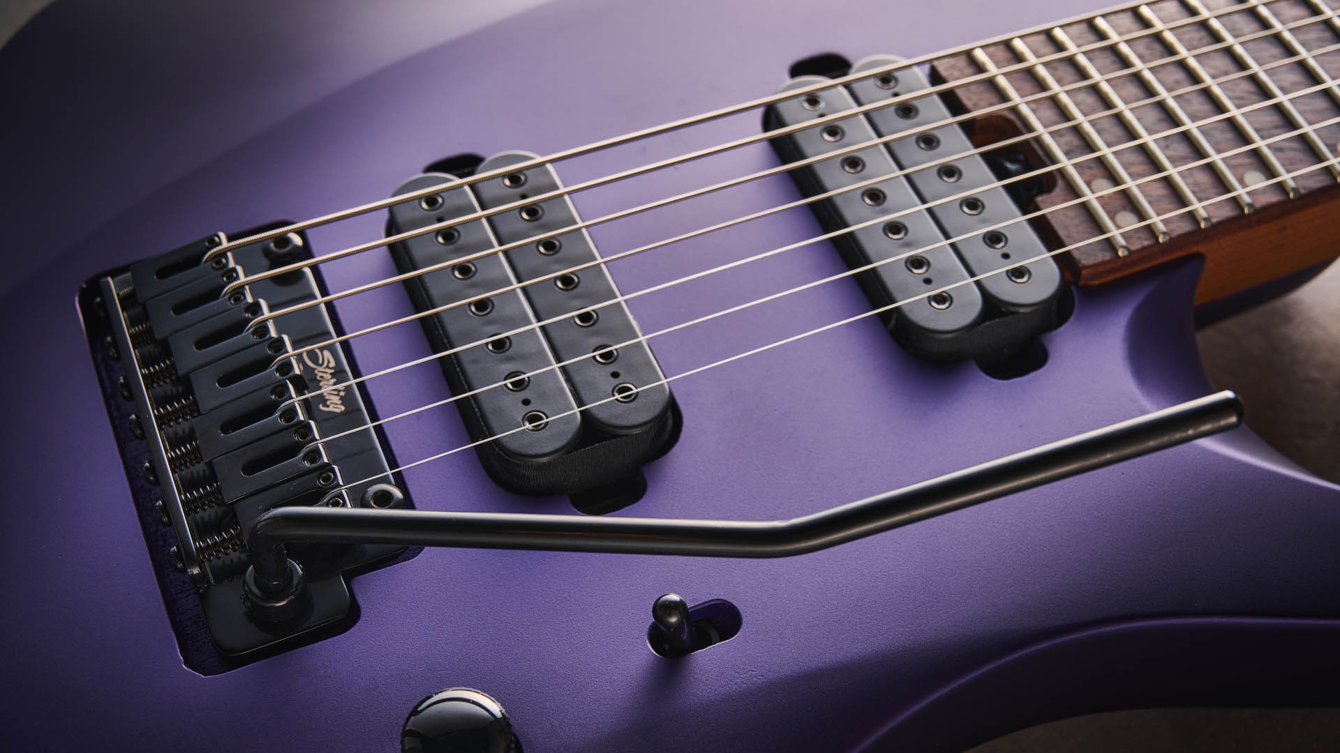 Sterling By Music Man Kaizen 7-string in Firemist Purple Satin, shot in close-up.