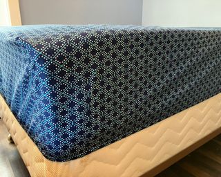 Tempur-Pedic mattress topper on mattress covered with blue geometric pattern bed sheets