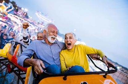 A happy couple ride a roller coaster.