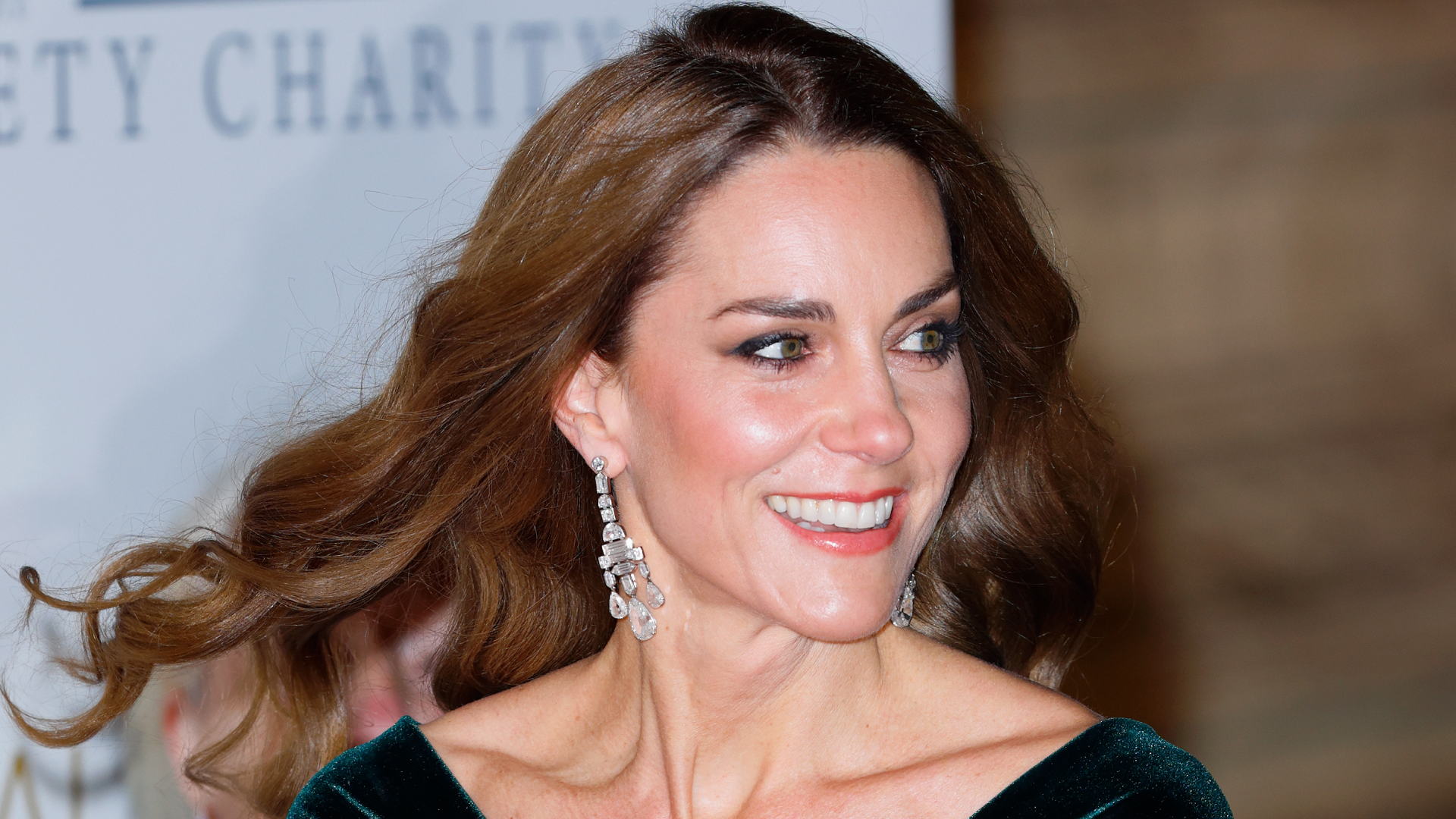 Princess Kate wearing a green gown and diamond chandelier earrings and smiling