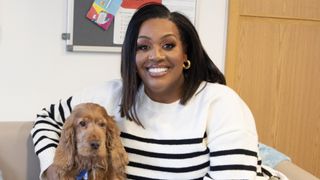 Alison Hammond in a black and white jumper sits alongside spaniel Nelly in For the Love of Dogs with Alison Hammond