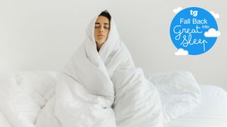 A woman wrapped up in a white duvet looking tired and miserable after struggling with winter insomnia