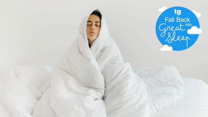 A woman wrapped up in a white duvet looking tired and miserable after struggling with winter insomnia