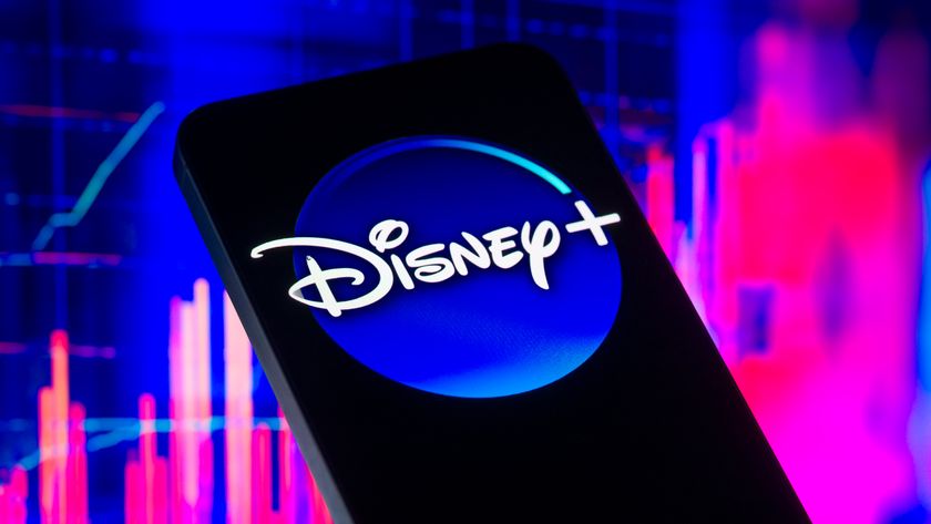 The Disney Plus logo is displayed on a mobile phone with blue and pink background