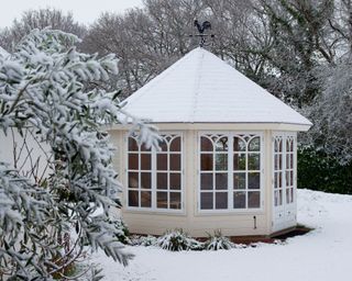 Summerhouse covered in snow in a garden