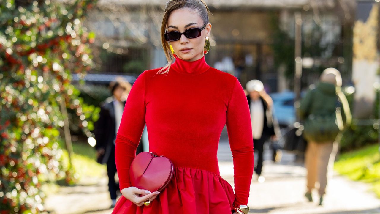 woman walking down the street wearing a red dress and holding a heart-shaped bag - Romantic perfumes