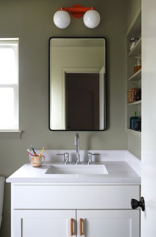 A bathroom with sage green walls and white fixtures