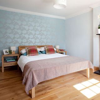 guest bedroom with wooden flooring and wallpaper on wall