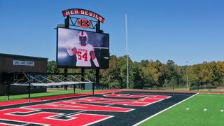 A Georgia High School videoboard, featuring a football player in uniform, shines bright on a sunny day.
