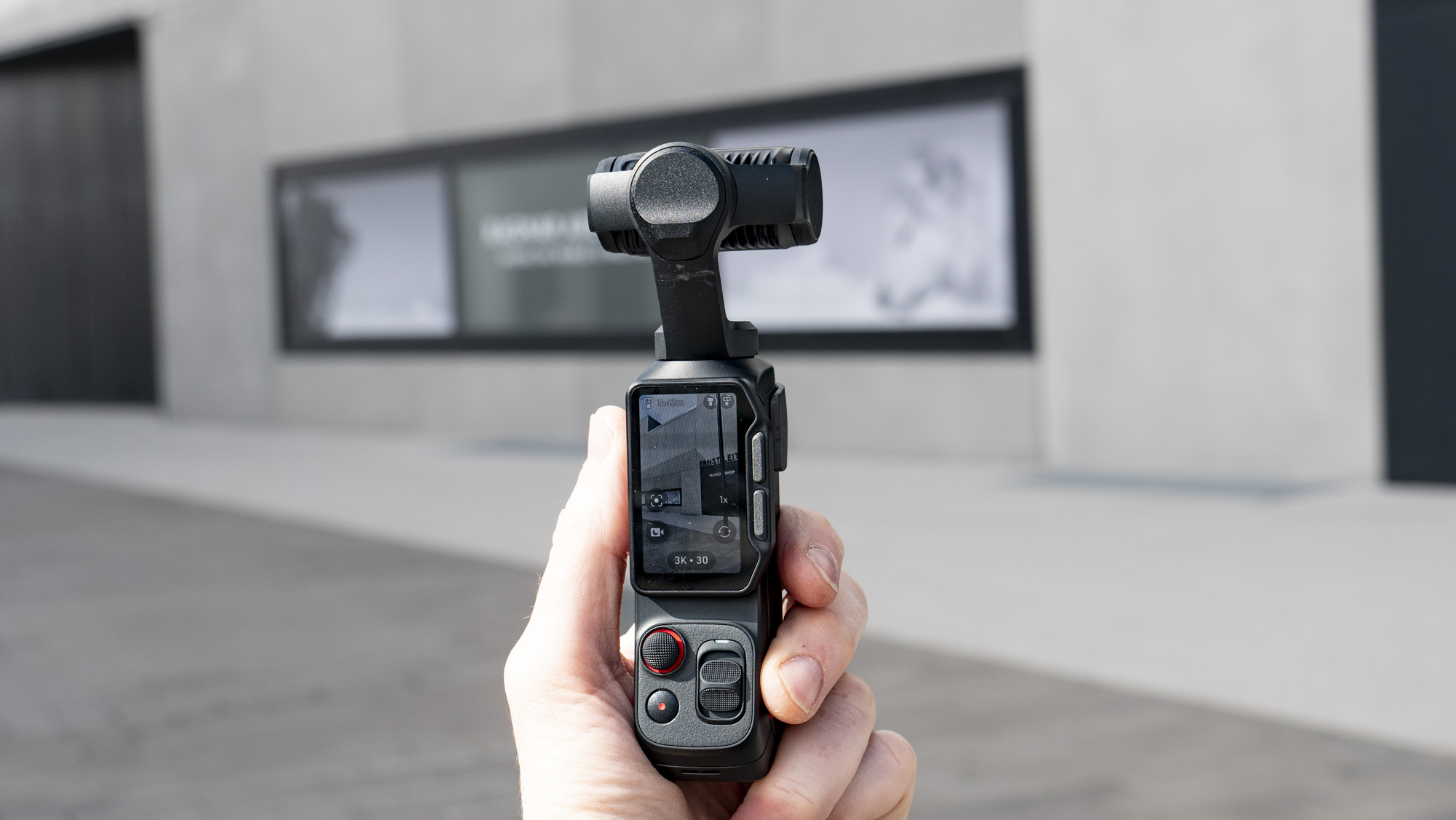 Insta360 Luna Ultra vlogging camerain the hand, outdoors in a grey urban scene