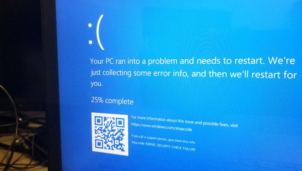 A flatscreen monitor displays the Windows 10 &#039;blue screen of death&#039; indicating a system failure.