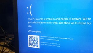 A flatscreen monitor displays the Windows 10 'blue screen of death' indicating a system failure.