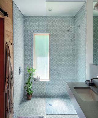wet room with frameless shower panel and pale blue hexagonal mosaic style splashback