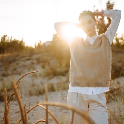 A woman on the beach in autumn, wearing a beige knitted jumper