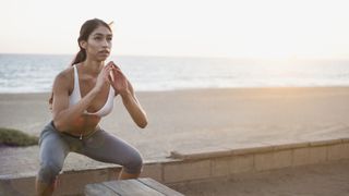 Young woman doing squat jumps on beach