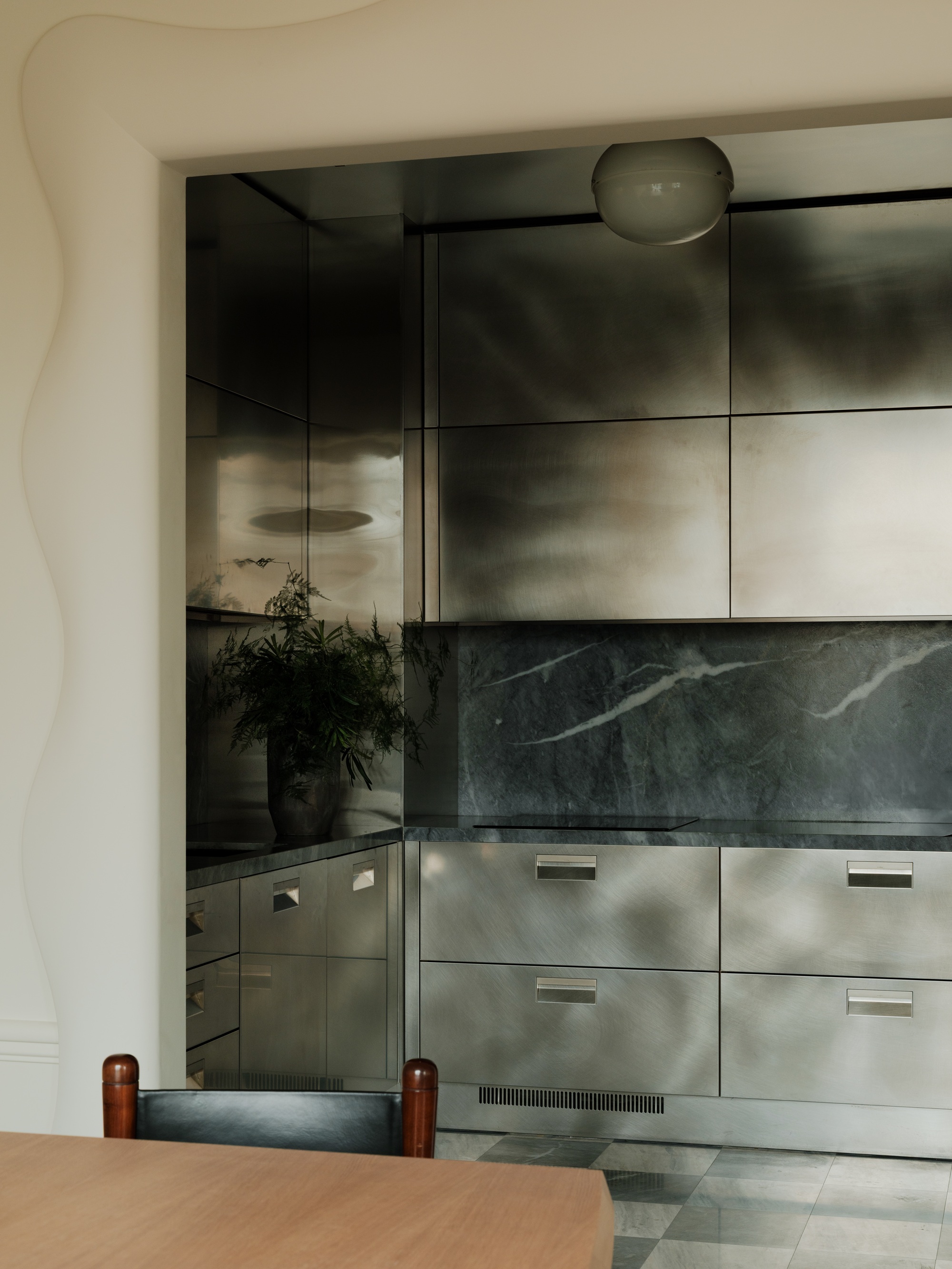 a dark gray stainless steel kitchen with a marble backsplash and checkerboard floors