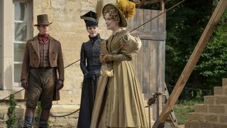 Joe Armstrong as Mr Washington in a brown suit and hat and red tie, Suranne Jones as Anne Lister in a tall black hat and dress and Sophie Rundle in a beige dress and yellow feathered bonnet in Gentleman Jack.