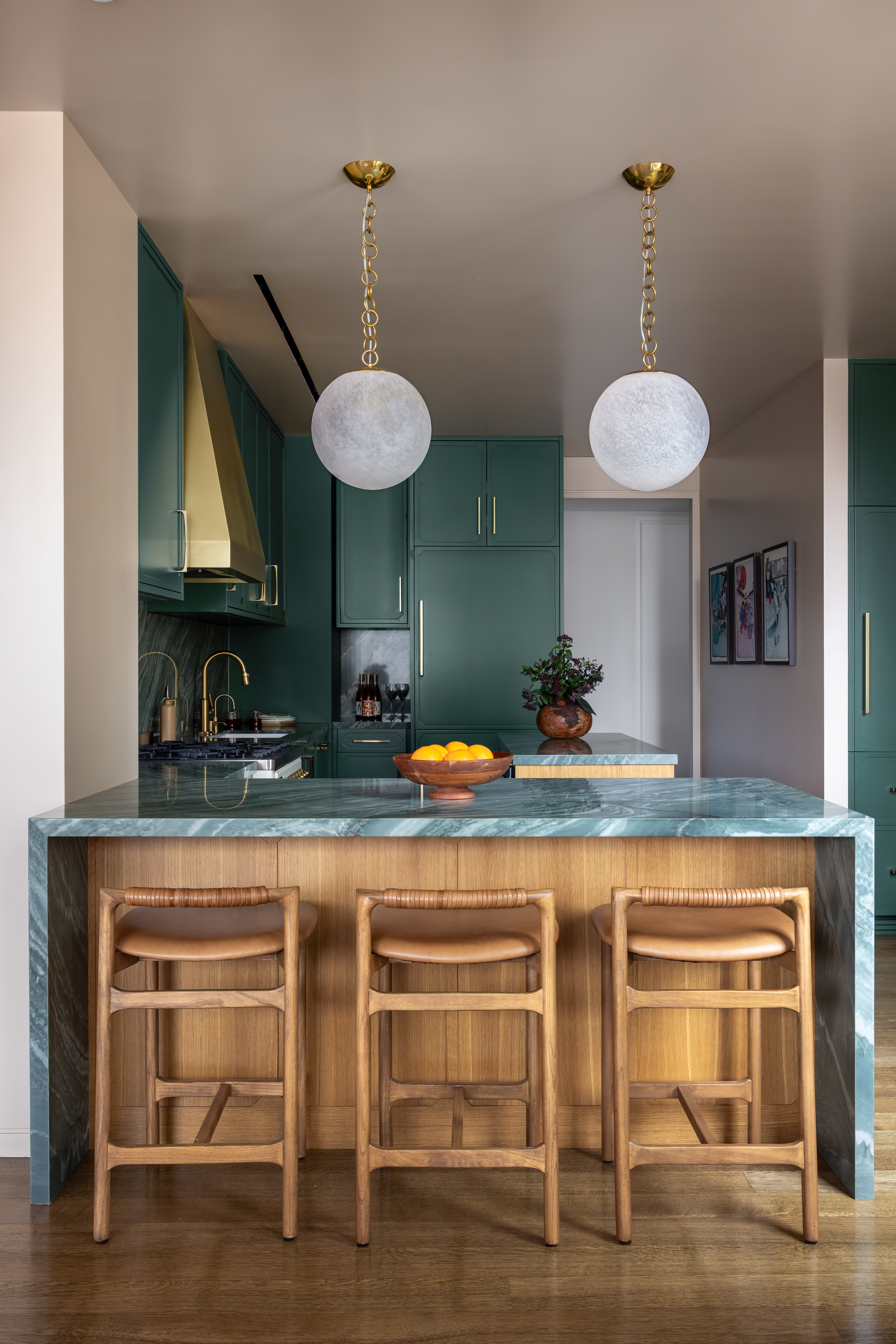 A kitchen with deep green interiors, and two pendant lights 