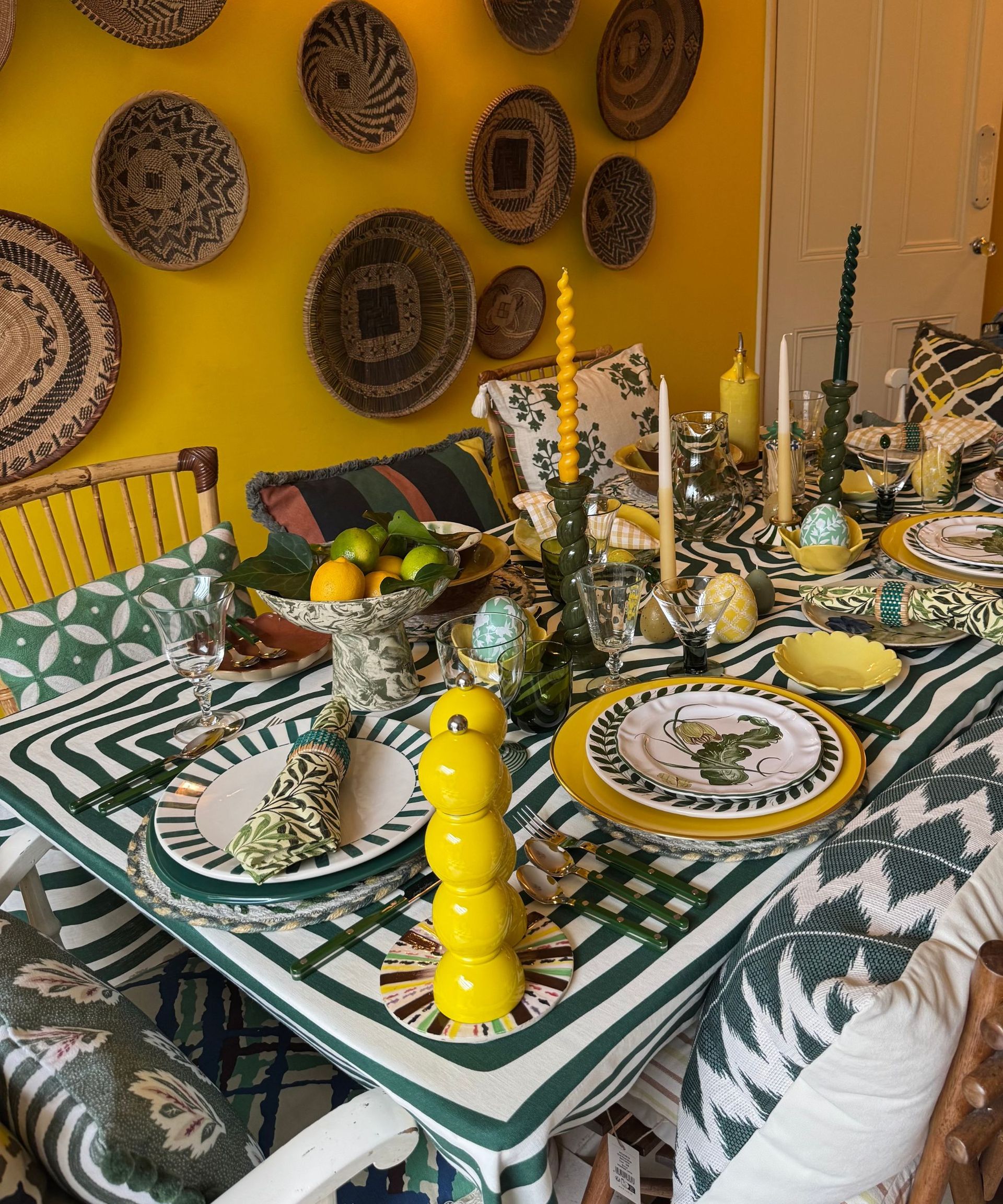 Green and yellow themed dining room and Easter table setting with mis-matched plates, napkins, candlesticks and decorative accessories