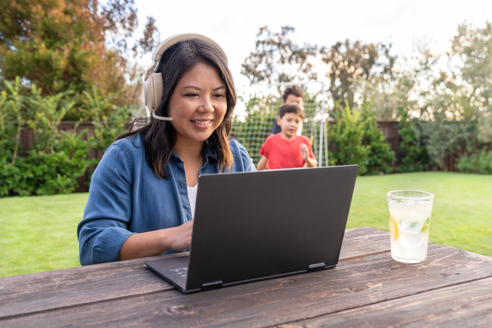 Woman working on laptop at bench in garden