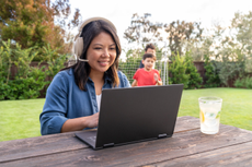 Woman working on laptop at bench in garden
