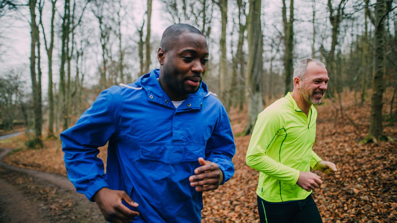 Two men run together through a wooded trail