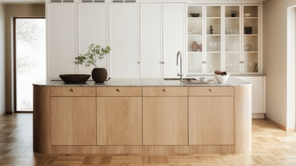 a contemporary minimalist kitchen with a large oak island with cabinets within and behind it, a row of white cabinetry, half with glass doors