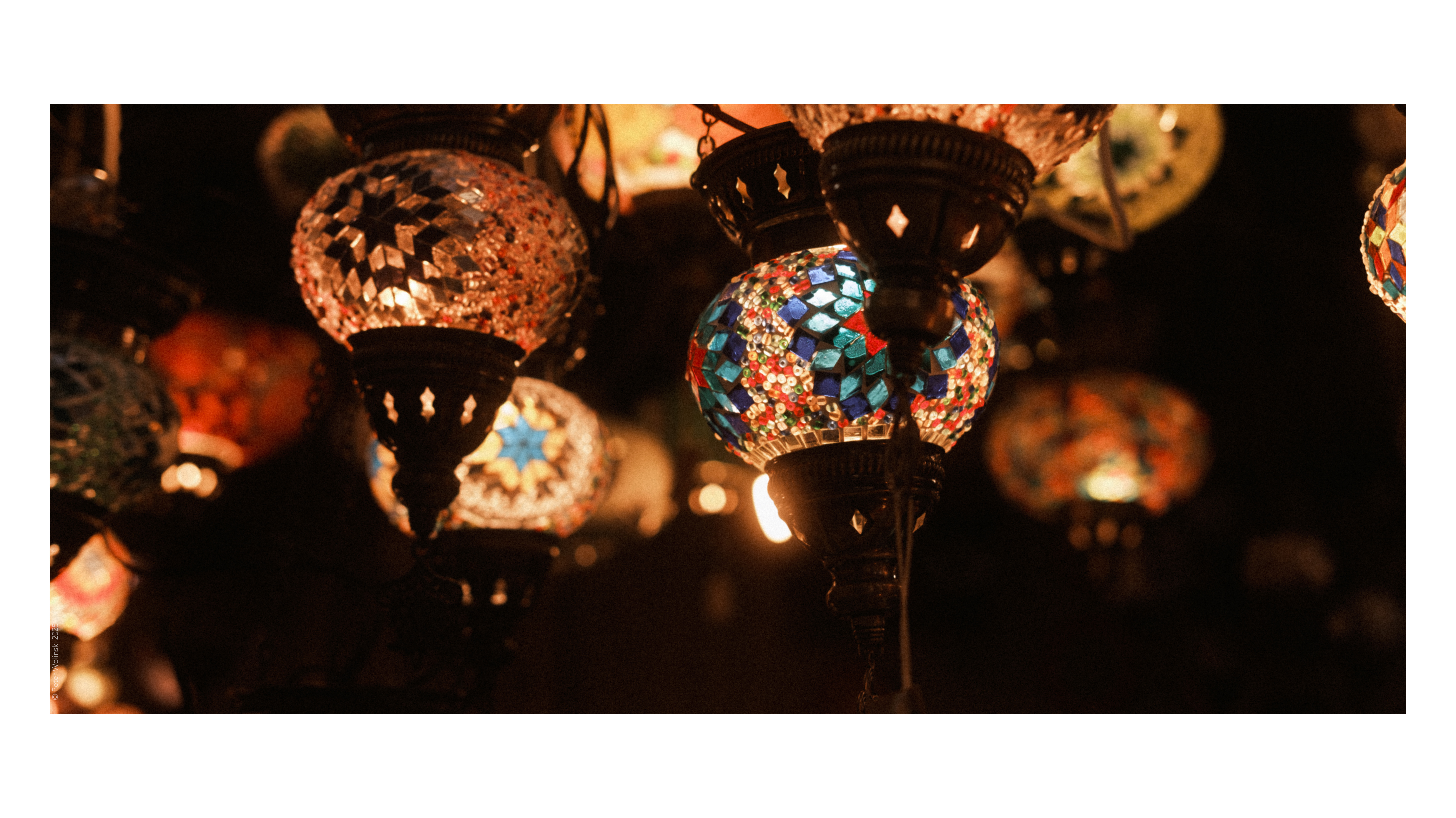A photo of a collection of hanging glass lanterns with ornate stained glass patterns, shot on the Fujifilm X-E4