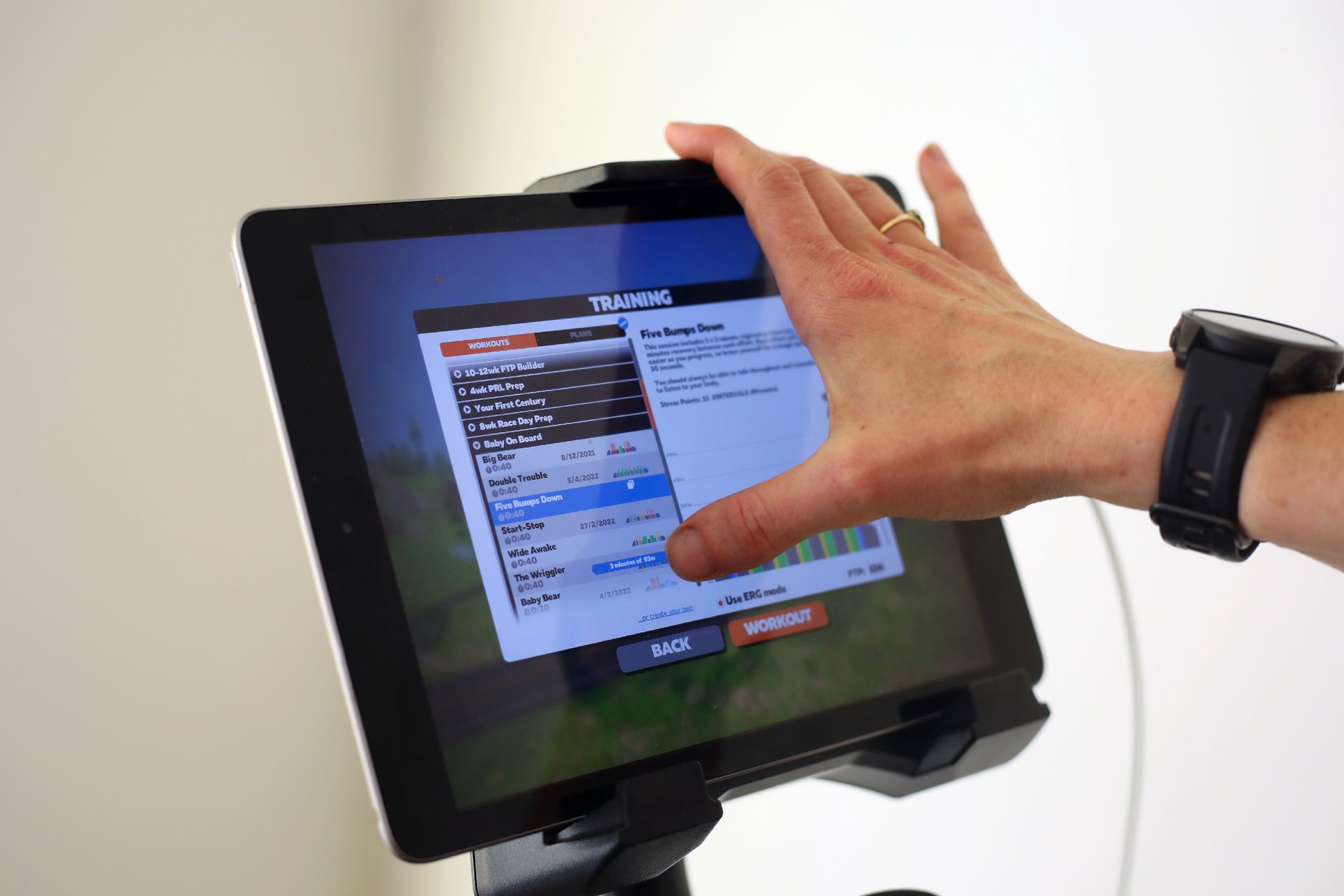 Female cyclist choosing one of Zwift's Baby on Board sessions on a tablet