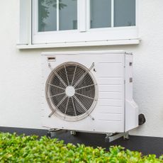 White heat pump on the side of a white house