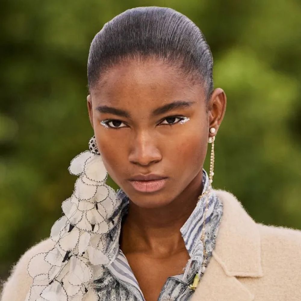 A model walking the runway at the Dior S/S 27 show with a silver winged eyeliner makeup look