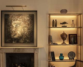 A living room wall lighting idea by John Cullen Lighting with Wallace Picture light, artwork over fireplace and a lit shelf
