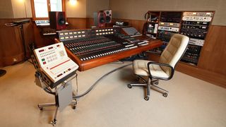 An empty recording studio with a chair pulls away from the desk