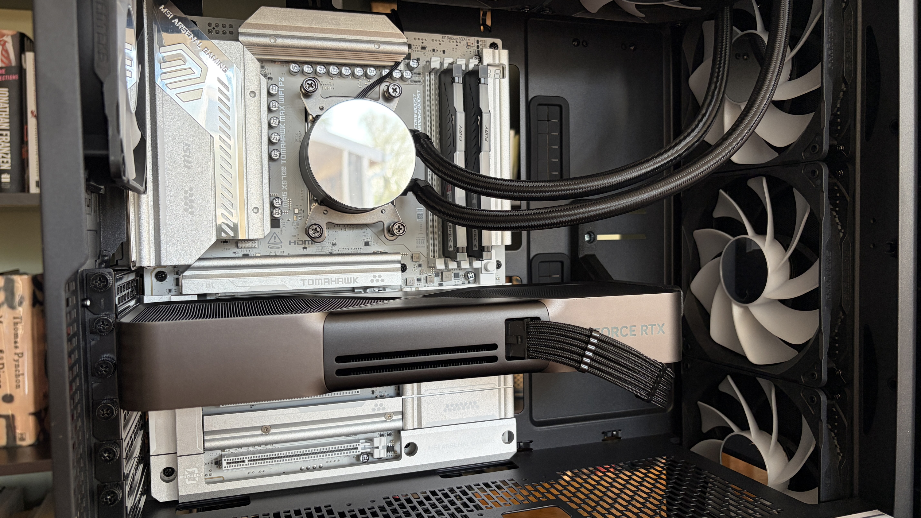Close-up of a sleek, modern MG-1 MK.II gaming PC's interior showcasing a silver motherboard, large graphics card, and cooling fans. The setup is tidy and high-tech.