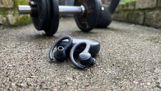 JLab Go Air Sport workout earbuds in front of some weights