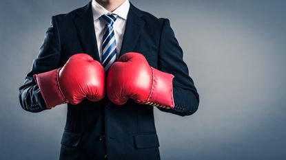 A man in a suit wears boxing gloves.