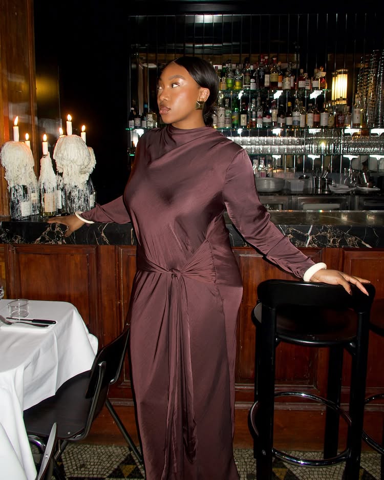 An image of @nnennaechem wearing a draped brown dress, one of the biggest party fashion trends of 2025.