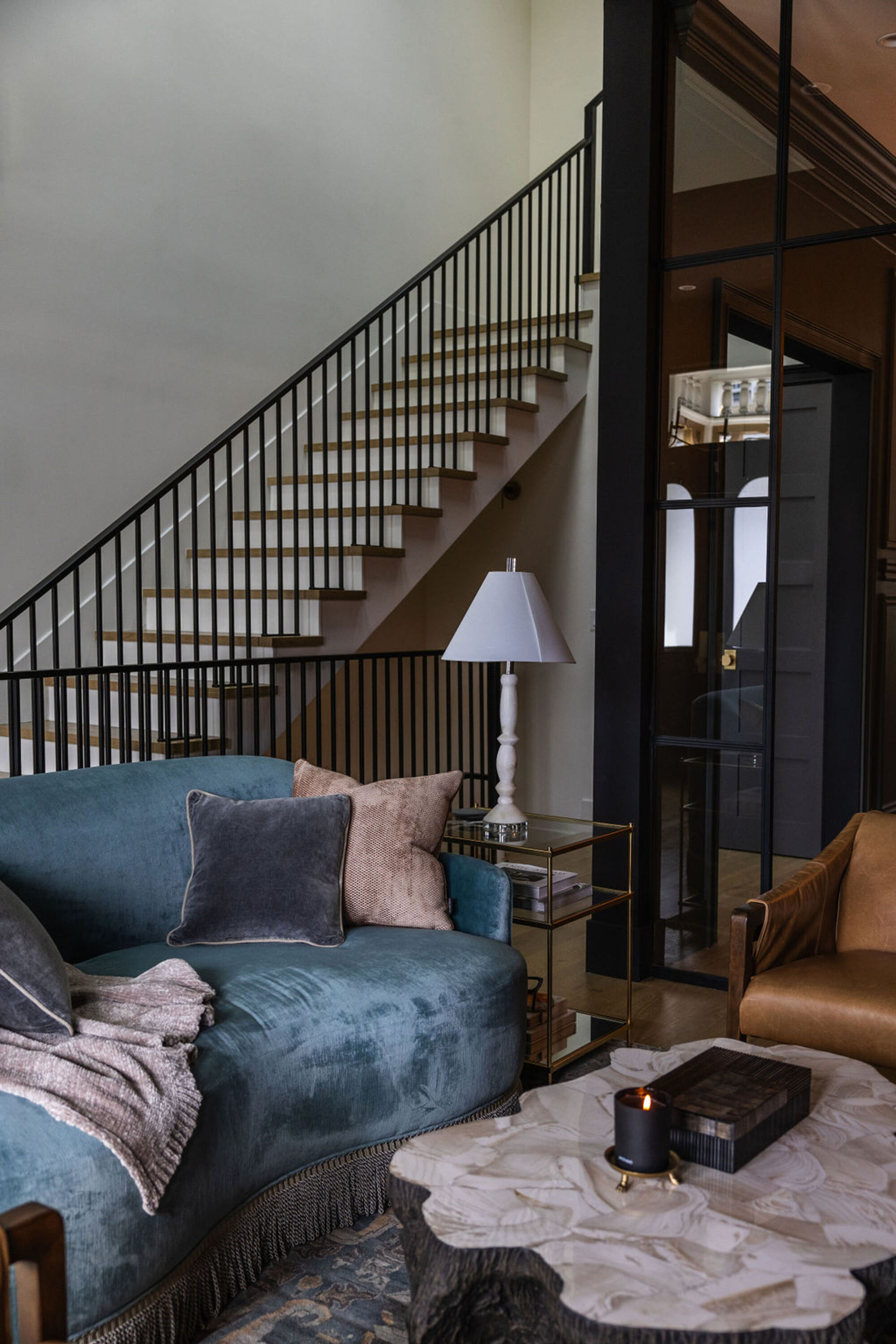 modern living room in front of staircase, with stump coffee table and blue curved velvet sofa with fringe