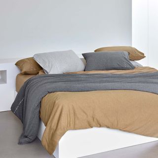 Boss Sense Bed Linen on a bed against a gray wall.