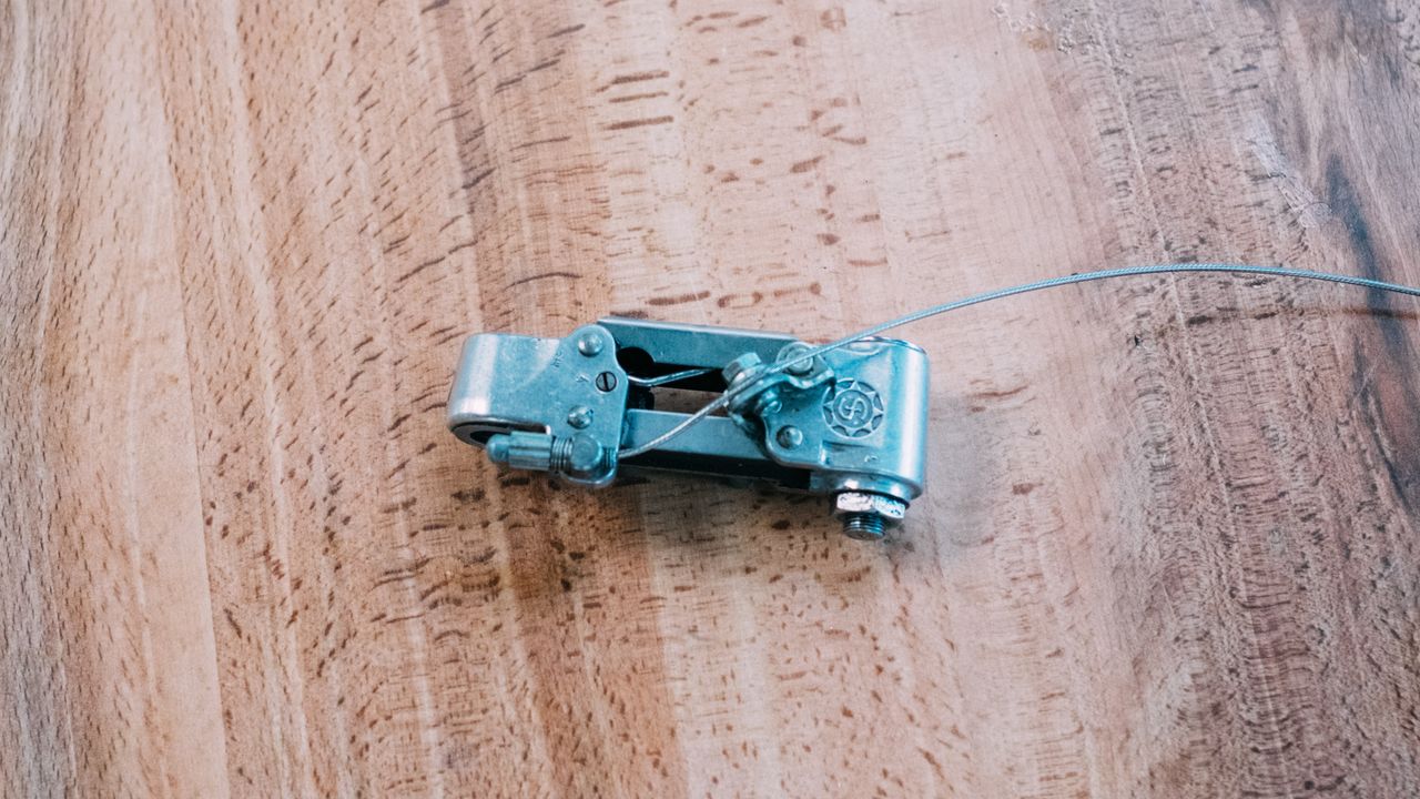 The silver body of a rear derailleur sits on a wooden table