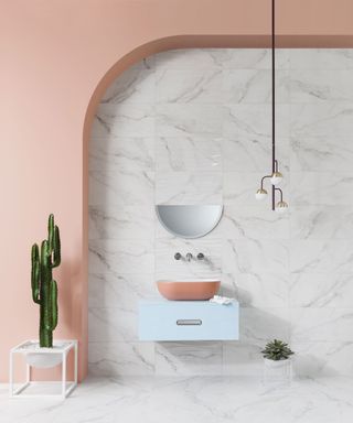 Marble effect wall and floor tiles next to a peach wall and a green cactus plant