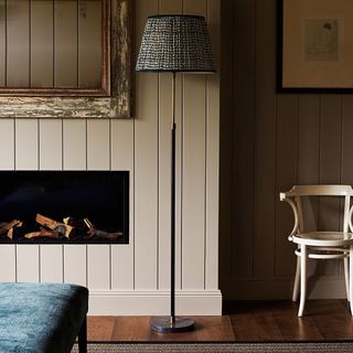 living room with shiplap walls, fireplace, floor lamp, chair, artwork