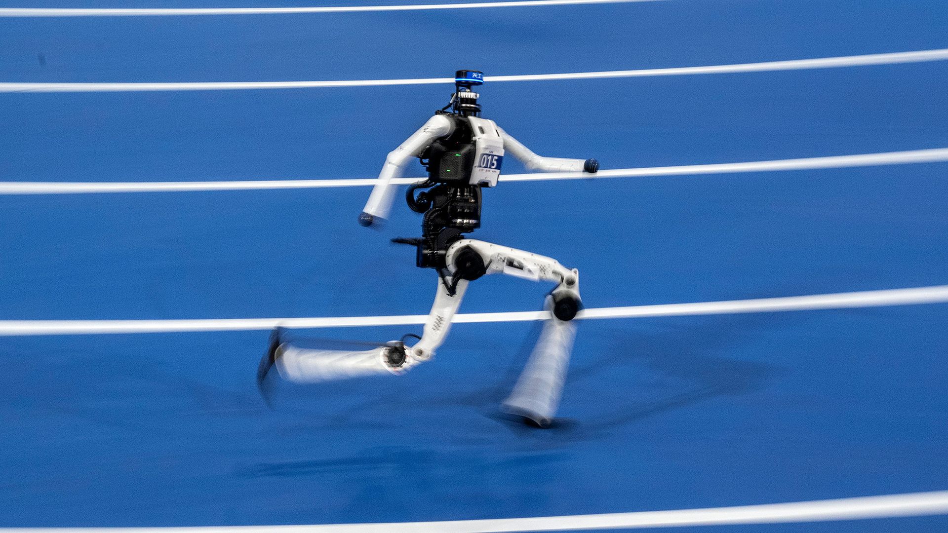 A black-and-white humanoid robot sprints on a blue track.