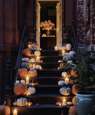 Halloween door decor ideas with pumpkins and candles in hurricane vases lining either side of the doorsteps