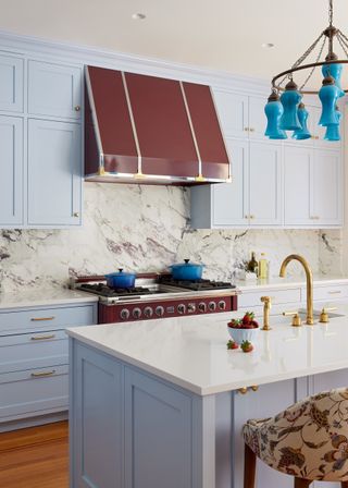 A kitchen with icy blue and range hood in maroon