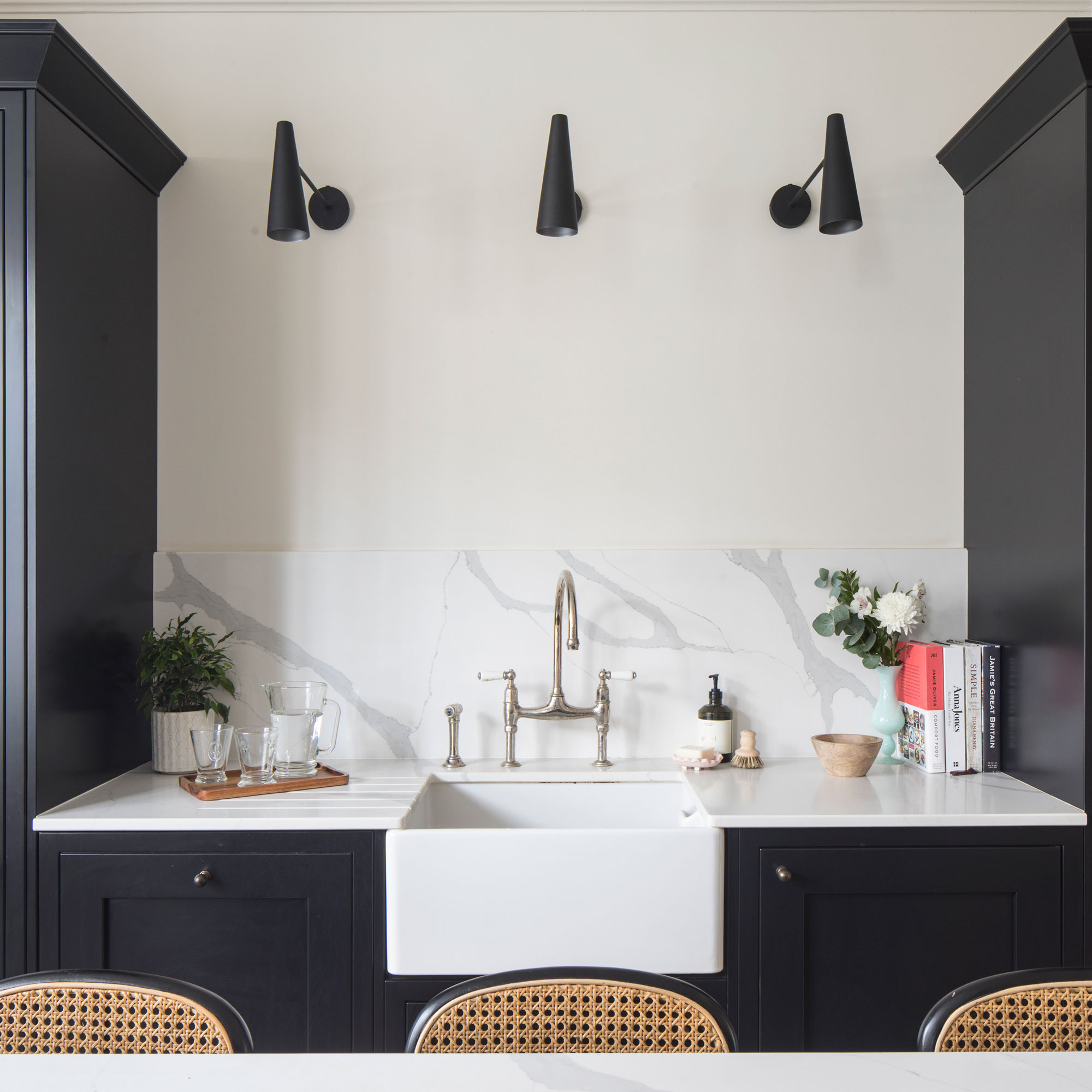 White kitchen with dark navy cabinetry and wall lights