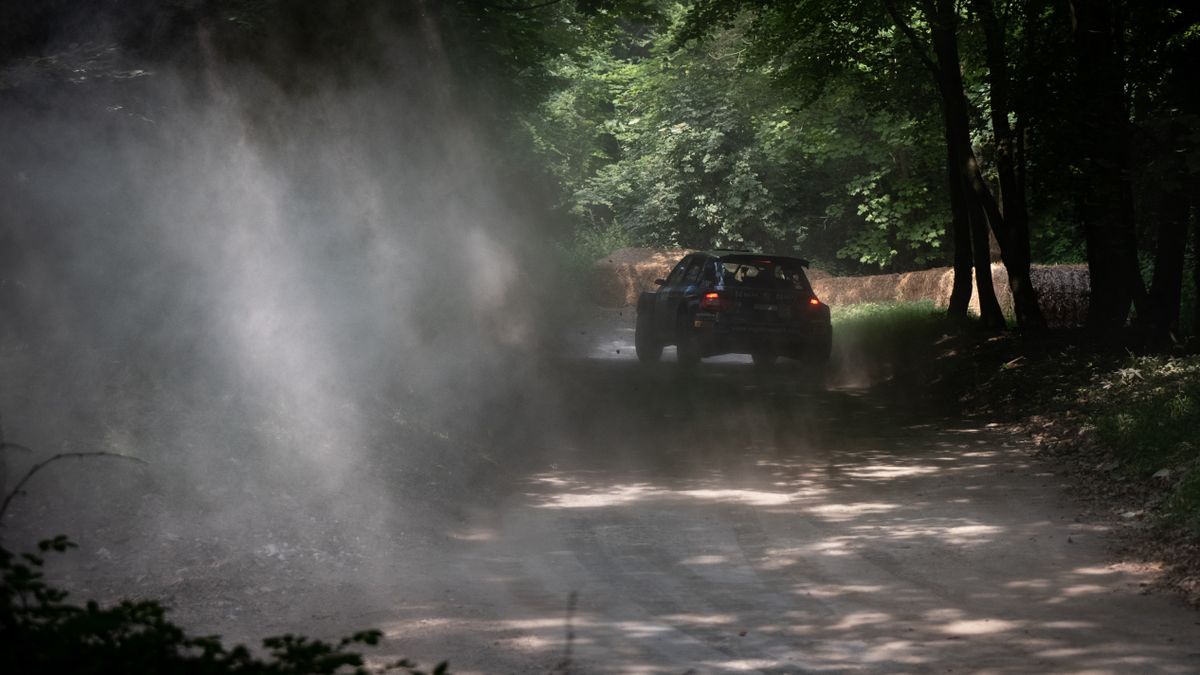 A rally car turning the corner of a race track at Goodwood