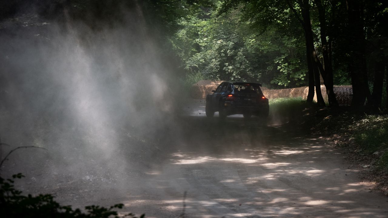 A rally car turning the corner of a race track at Goodwood