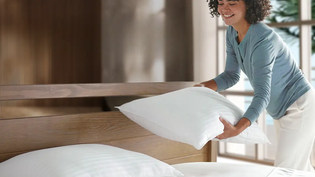 Woman placing the Beckham Hotel Collection pillows on the bed