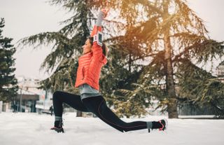 Female runner stretching in the snow